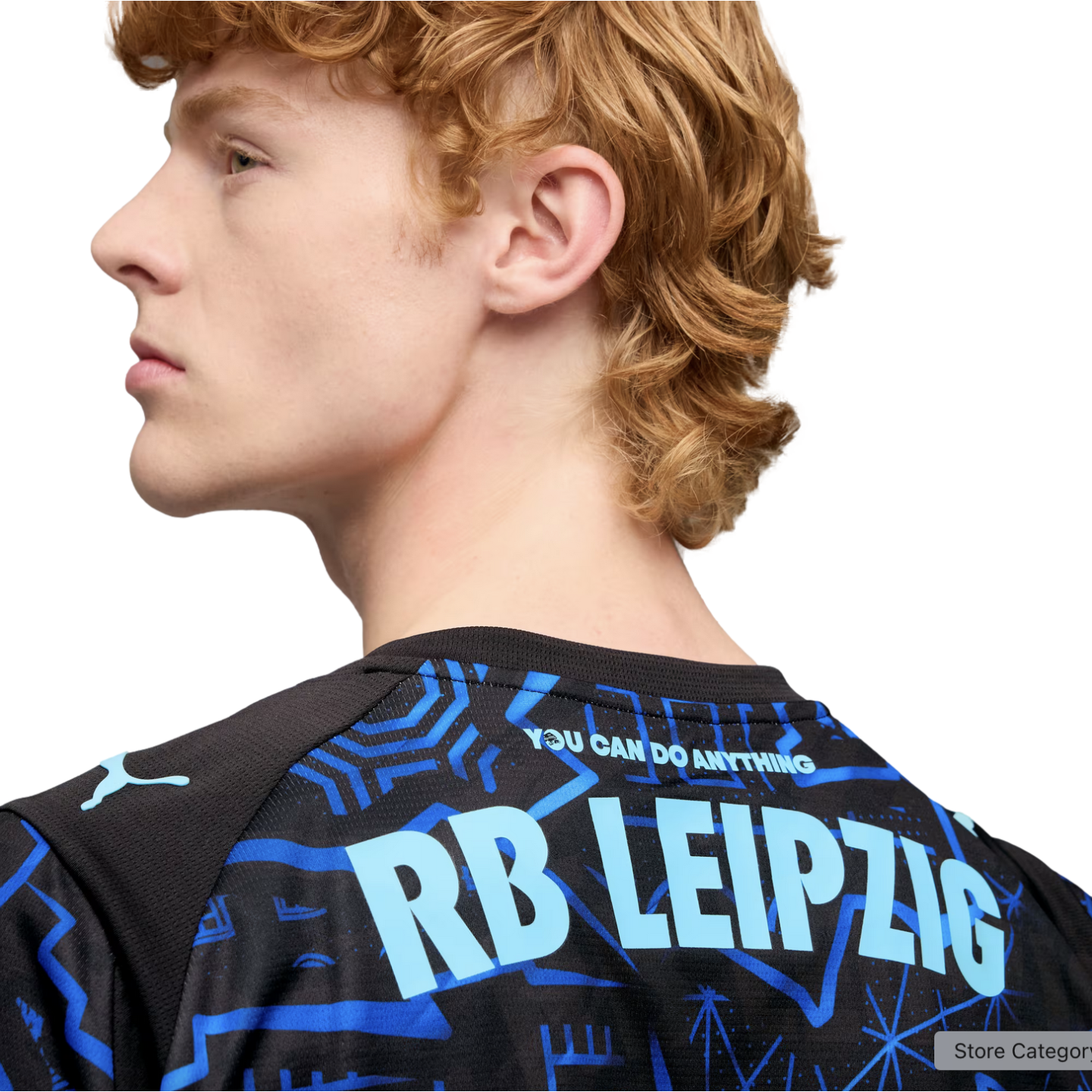 Profile of a man with wavy reddish hair wearing a black Puma jersey with "RB LEIPZIG" and "YOU CAN DO ANYTHING" printed in light blue on the back.