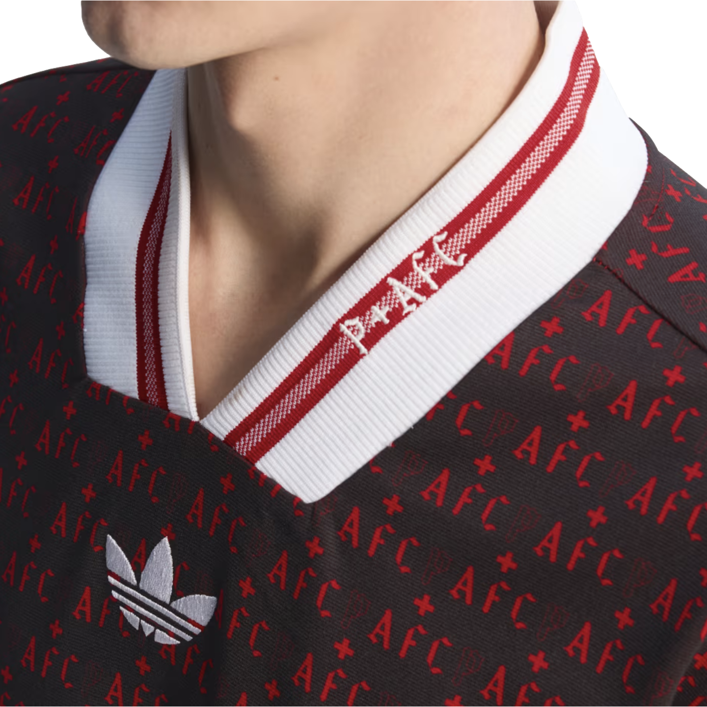 Close-up of a black Adidas jersey featuring a red repeating "AFC" pattern and a white V-neck collar with red stripes and "P+AFC" embroidery.