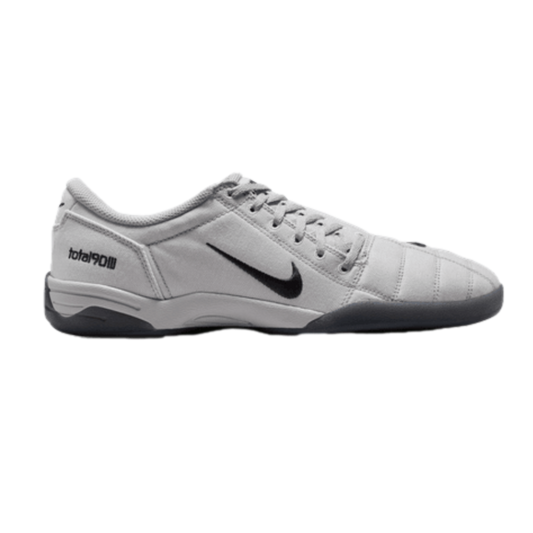 Profile of a light grey Nike Total 90 III indoor soccer shoe featuring a black swoosh and a dark grey sole.