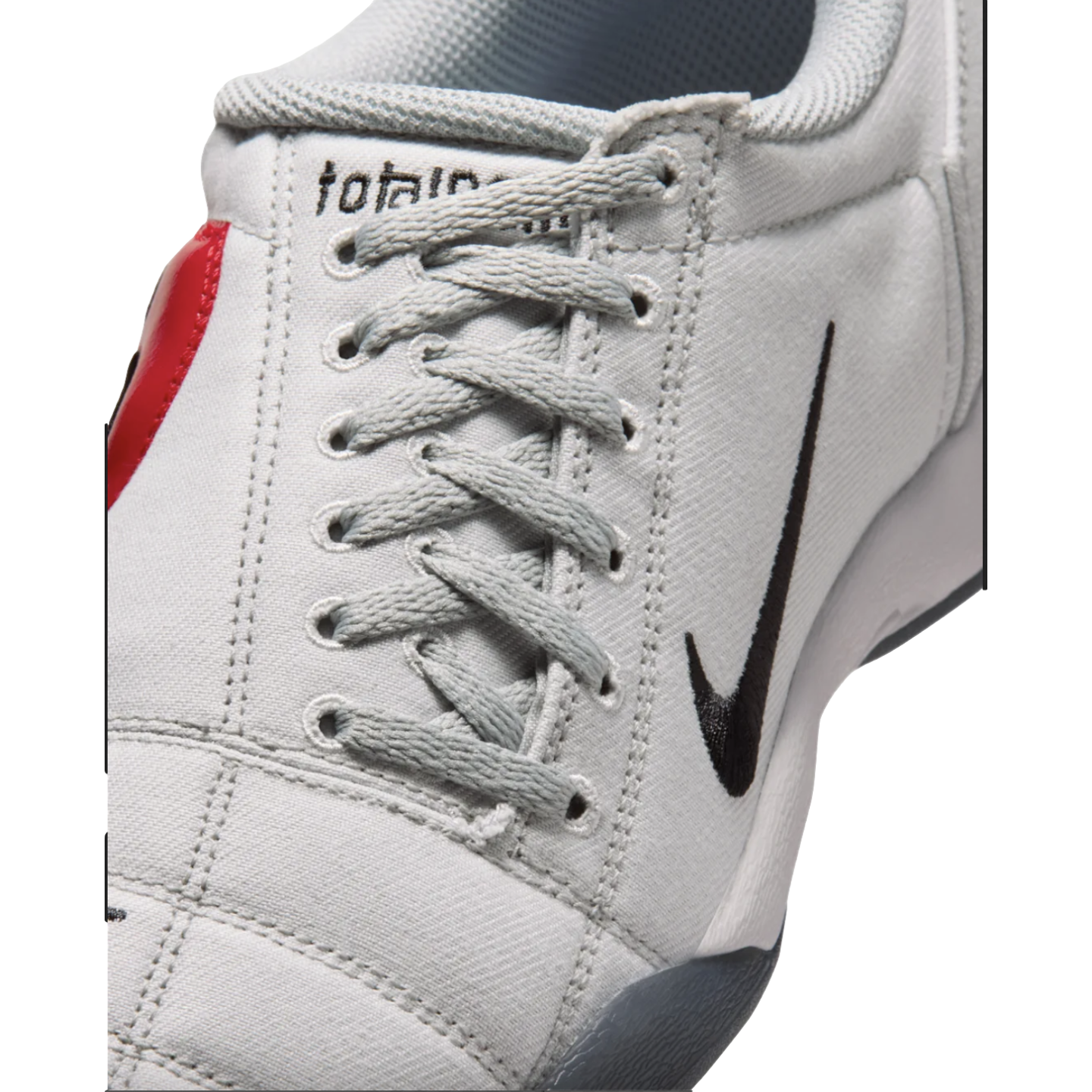 Close-up of a light gray textured Nike sneaker with gray laces and a black swoosh logo on the side.