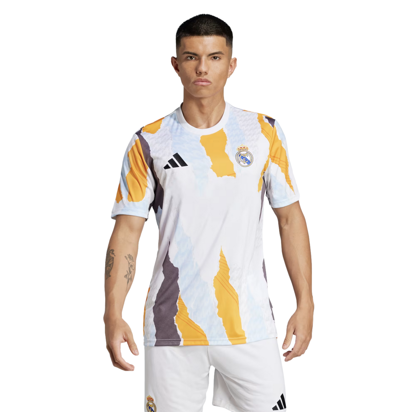 A model wearing a Real Madrid pre-match jersey and white shorts against a black background. The white shirt features a bold, jagged abstract pattern in yellow, grey, and light blue, with the black Adidas logo and Real Madrid club crest on the chest.