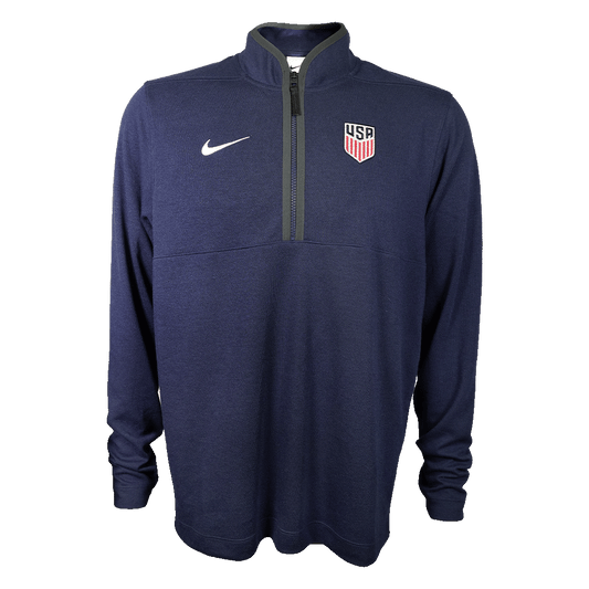 Dark blue long-sleeve Nike quarter-zip pullover with a white swoosh and USA Soccer crest, shown on a solid green background.
