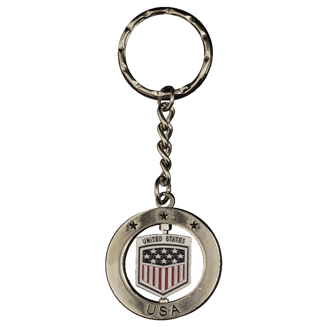 Silver-toned metal keychain with a spinning central shield featuring a US flag motif and "UNITED STATES." The outer circular frame has stars and "USA."